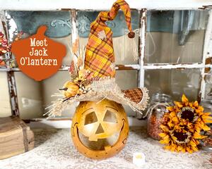 This is a pumpkin decoration. It is made from a real gourd.  It has a scarecrow face and a handmade witch hat. The hat is orange plaid.  